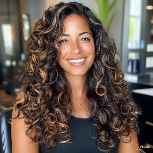 Mulher morena iluminada com cabelo cacheado sorrindo no salão de beleza