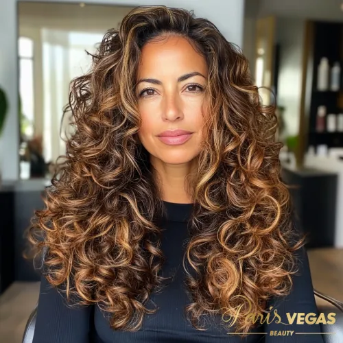 Cabelo cacheado de morena iluminada, exibido com charme no salão Paris Vegas Beauty em São Paulo.