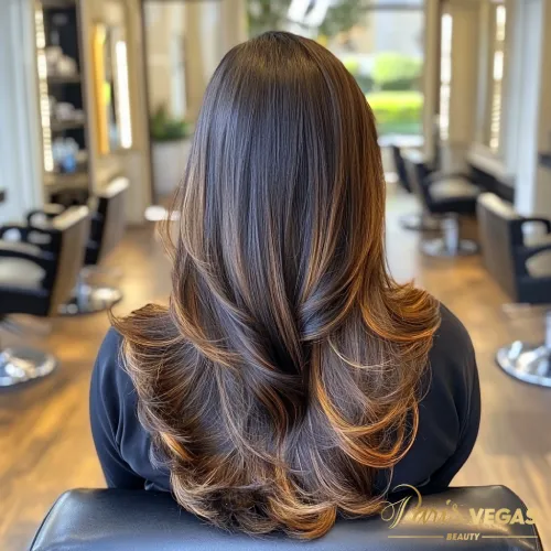 Mulher de costas com cabelo morena iluminada caramelo em salão de beleza em Moema.