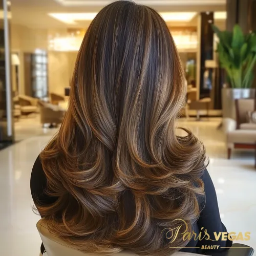 Mulher de costas sentada em ambiente luxuoso com cabelo morena iluminada caramelo.