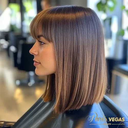 Mulher de lado com cabelo curto e radiante em tom de morena iluminada, em um ambiente elegante.