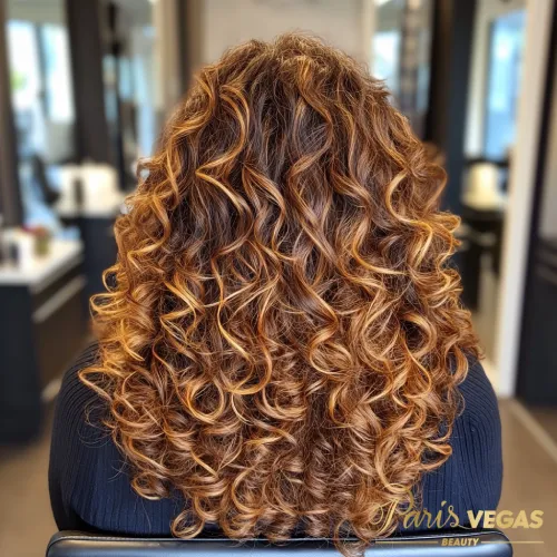 Cabelo cacheado de morena iluminada, capturada em um momento elegante no salão Paris Vegas Beauty em São Paulo.