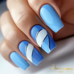 Unhas decorada azul com curvas em branco e prata, design elegante e sofisticado, perfeito para quem busca uma manicure moderna e refinada em Moema, São Paulo.