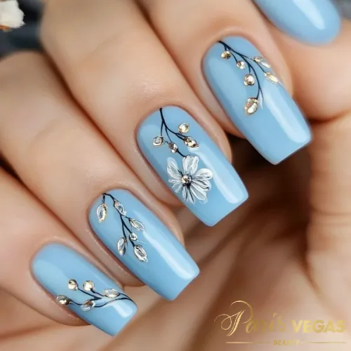 Unhas decorada azul com design floral suave, manicure delicada e elegante, perfeita para quem busca um visual sofisticado em salão de cabeleireiro em Moema.