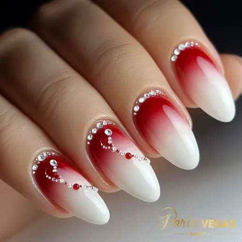 Decorações em unhas vermelhas com efeito ombré e strass, design sofisticado e encantador.