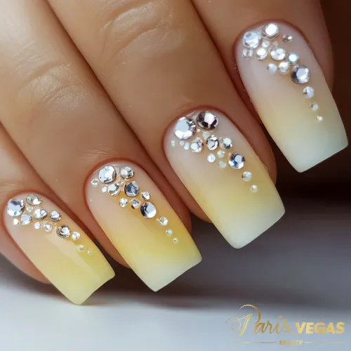 Unhas amarelas com efeito degradê e pedrarias, feitas por manicure profissional no Paris Vegas Beauty, Zona Sul de São Paulo.