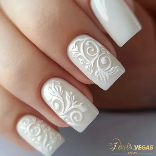 Unhas decoradas branco com arabescos, criadas por manicure, oferecendo um visual clássico e sofisticado.