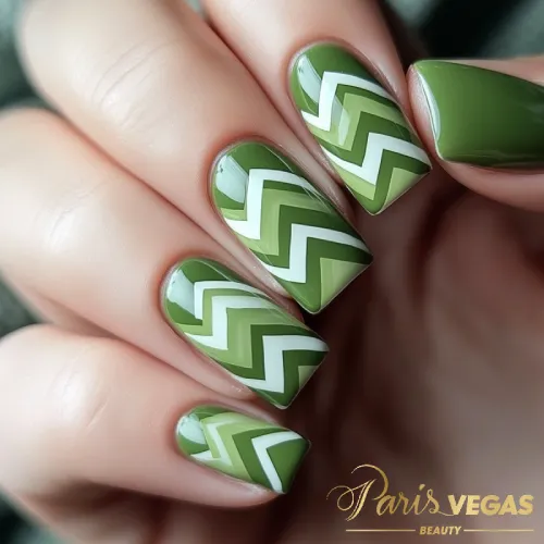 Unhas em verde com estampa Chevron, design moderno e geométrico.