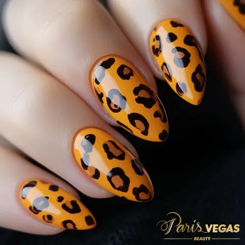 Unhas laranja com estampa animal print oncinha, destacando um design ousado e moderno.