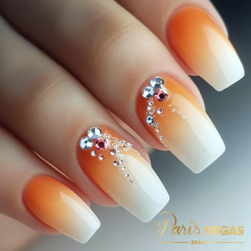 Unhas laranja decoradas com strass, destacando um design de manicure elegante e moderno.