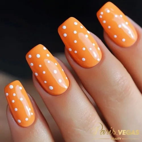 Unhas laranja decoradas com estampa de poá, destacando um design divertido e moderno.