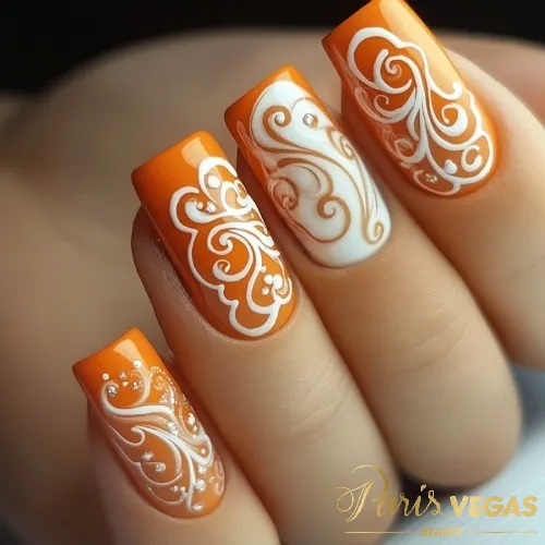 Unhas laranja decoradas com arabescos brancos, destacando um design elegante e moderno.