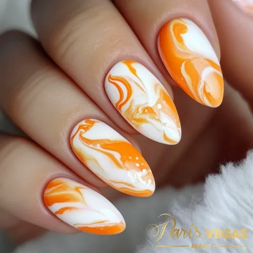 Unhas laranja com efeito marmorizado, destacando um design artístico e moderno.