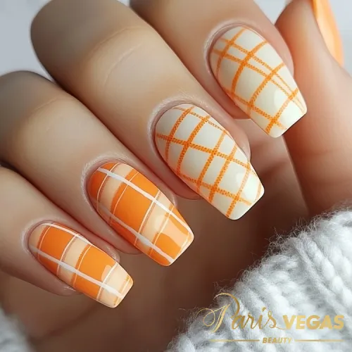 Unhas laranja com design de linhas finas quadriculadas, destacando um estilo moderno e geométrico.