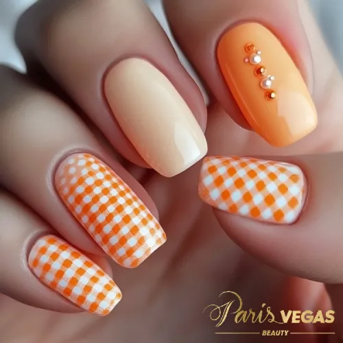 Unhas laranja com estampa xadrez vichy, destacando um design criativo e estiloso.