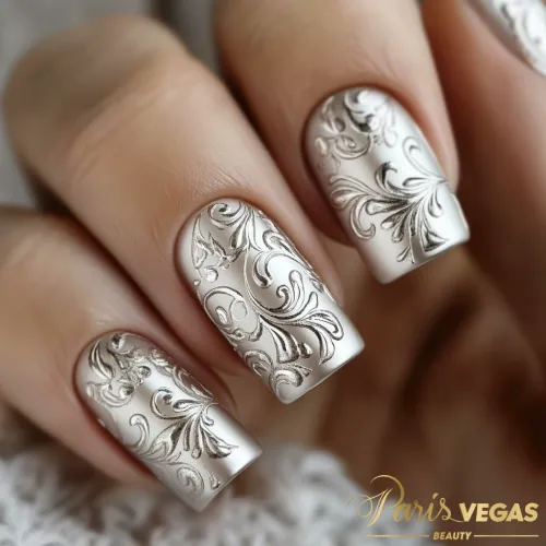 Unhas prata decoradas com arabescos clássicos, criando um design elegante e refinado, feito no salão de cabeleireiro Paris Vegas Beauty em Moema.