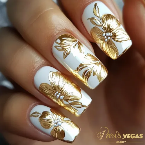 Unhas douradas com desenhos florais feitas no salão Paris Vegas Beauty em Moema.