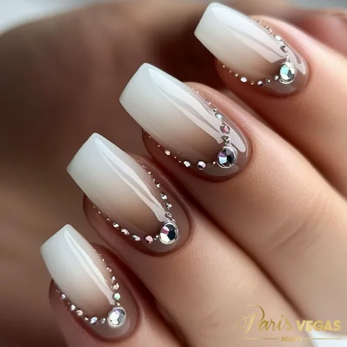 Unhas marrons com efeito degradê e pedrarias, criando um design elegante e luxuoso.