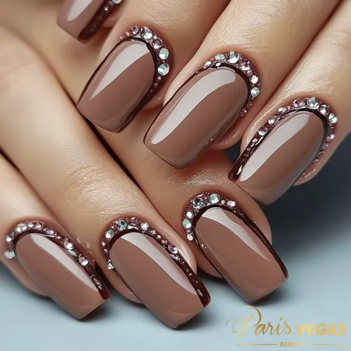 Unhas marrons com strass, criando um design sofisticado e brilhante.