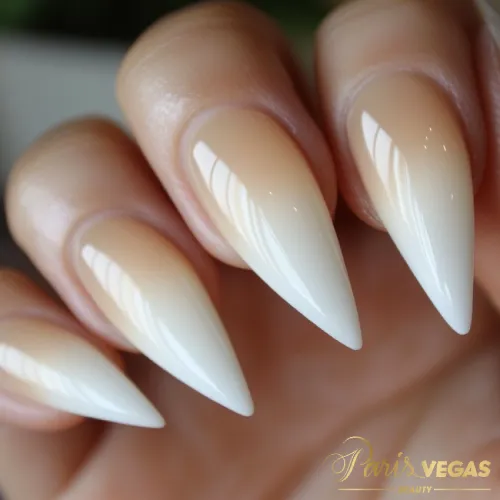 Unhas nude stiletto com efeito degradê, criando um visual elegante e sofisticado.